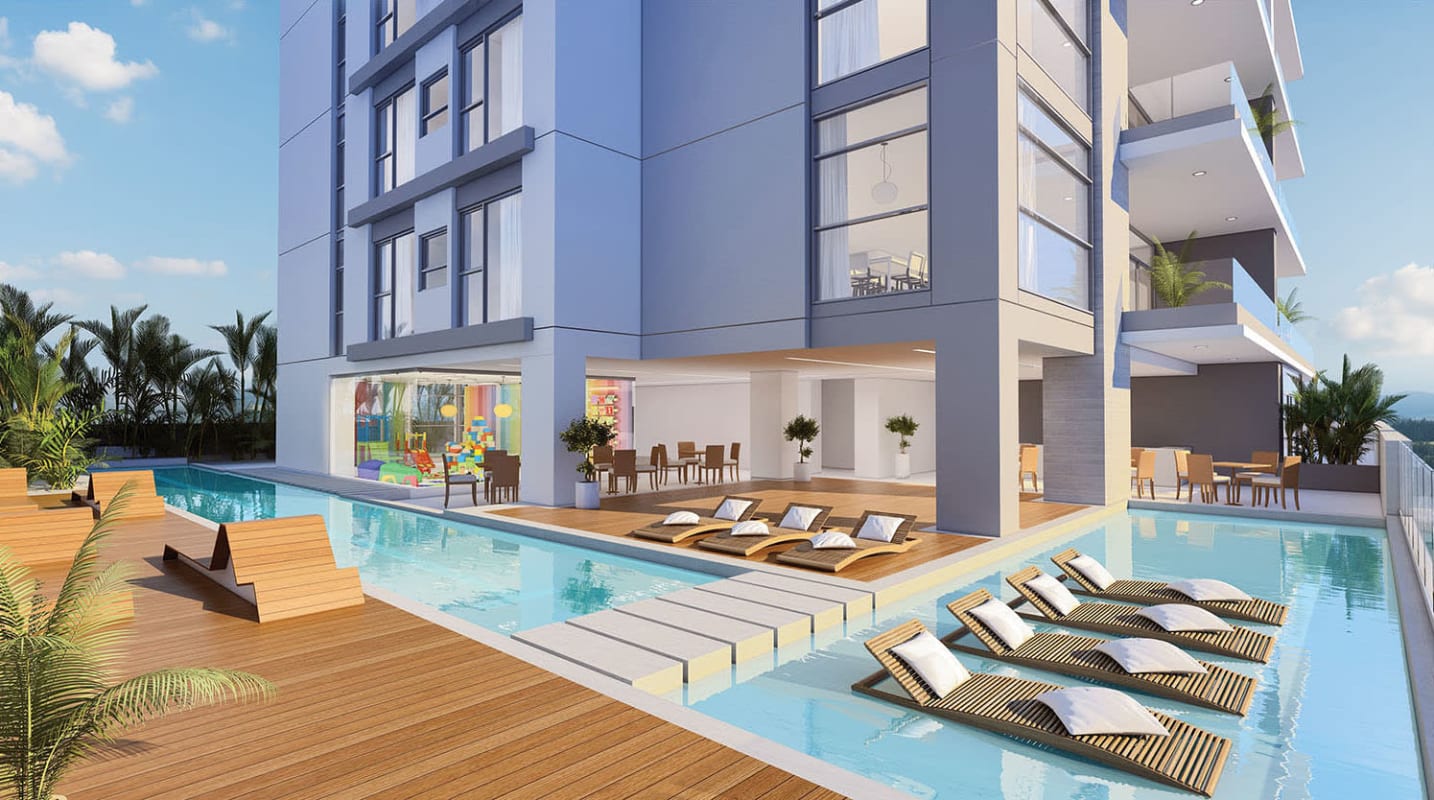 Swimming pool surrounded by wooden deck, lounge chairs and landscaping in Albatross Santa María luxury apartment