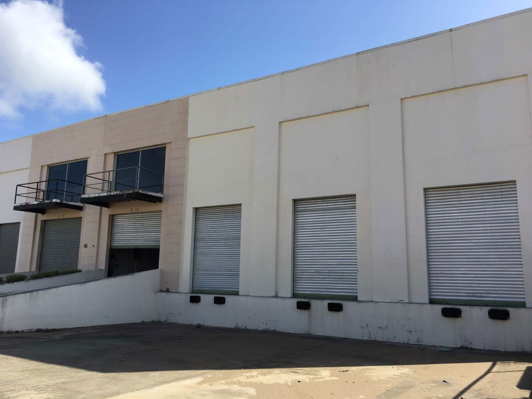 Industrial warehouse exterior with dock ramps roll-up doors and signage area in Panama