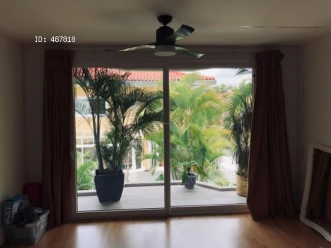 Large glass doors open to the garden from spacious living room with wood floors in Costa Serena