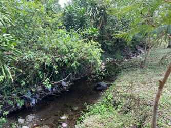 Open grassy land surrounded by trees and rolling hills under partly cloudy skies in Volcán Panama