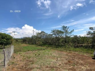 Wide open land with scattered vegetation, dirt path, and mountain range view in Potrerillos Panama for sale