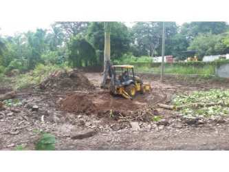 Excavator clearing construction site in Bejuco Panama with visible soil piles and vegetation