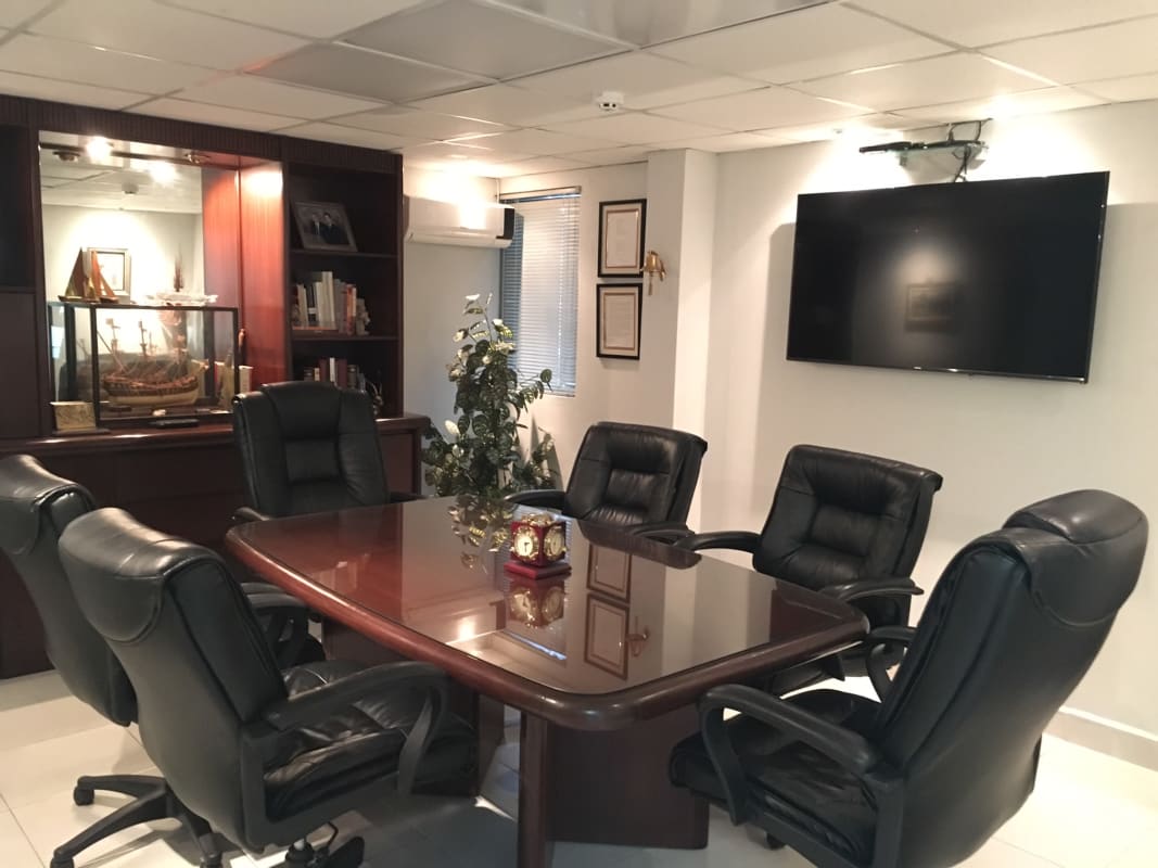 Executive conference room with wooden table, leather chairs and flat-screen TV at PH Eurocentro Panama