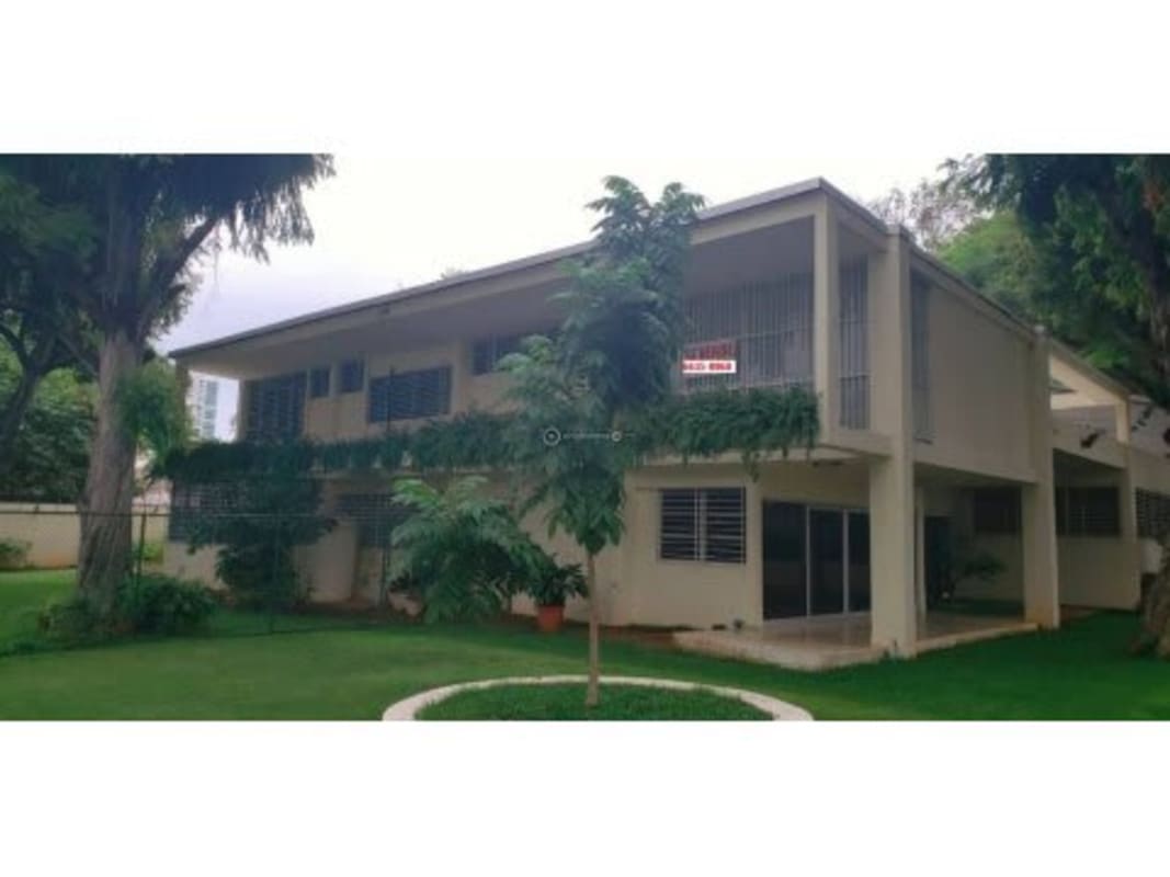 Side facade of two story house with large windows balcony mature landscaping Obarrio