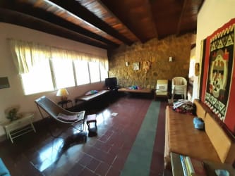 Spacious rustic living room with stone fireplace, wood beams and access to nature views in Panama country estate