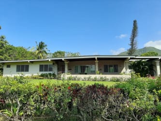 Front view of ranch-style house with large covered porch and vibrant gardens