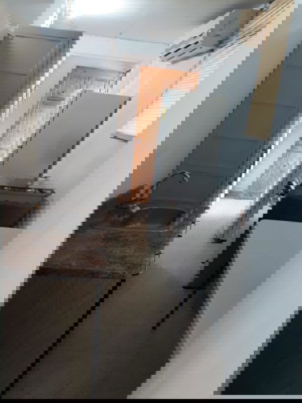 Small kitchen with gray cabinets, fridge, microwave, stove in studio rental Villa de las Fuentes Panama City