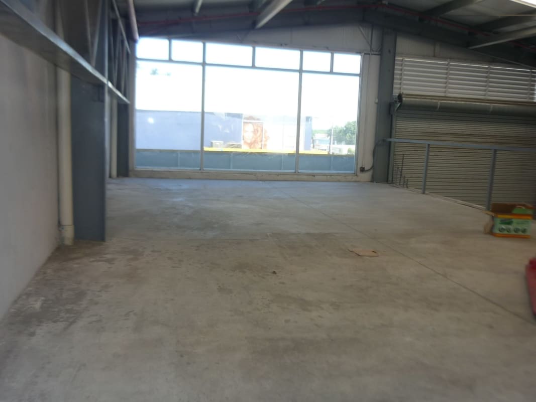 Empty retail commercial unit with glass doors, tiled floor, orange accents in warehouse complex Panama City