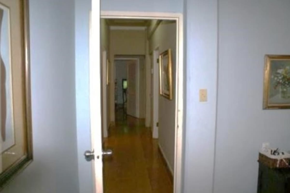 Traditional hallway with hardwood floors and framed art in Clayton family house Panama