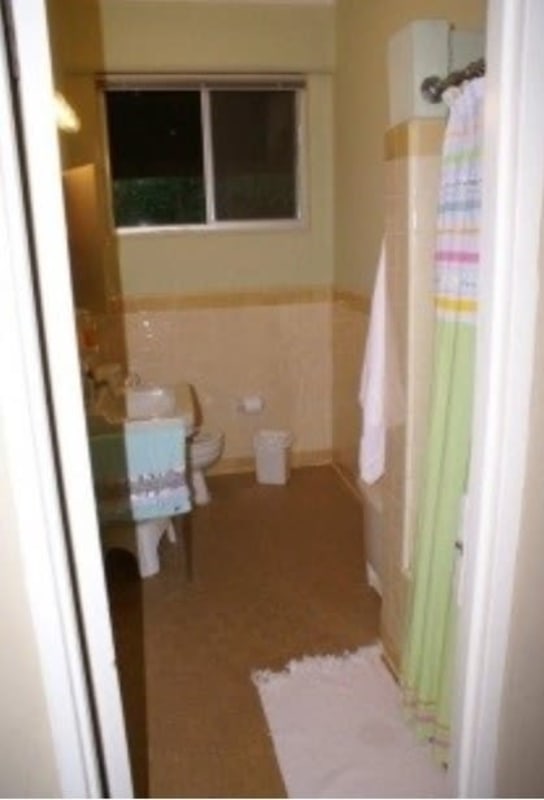 Functional residential bathroom with window, colorful curtain and beige tiles Clayton house for sale