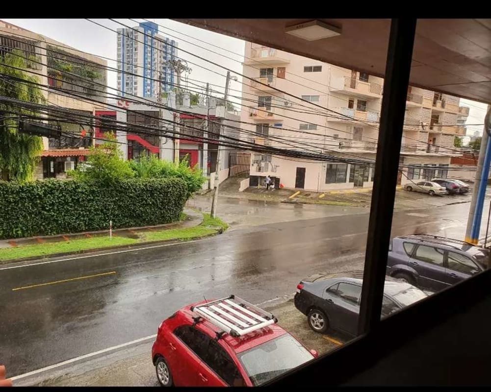 View of city street with parked cars and commercial buildings in San Miguelito Panama City