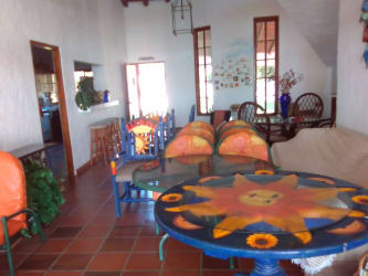 Rustic living and dining area with terracotta tiles, painted sun motif furniture in Playa Blanca beachfront villa