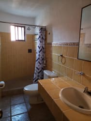 Rustic tiled bathroom with walk-in shower and window in Coronado beach rental Panama