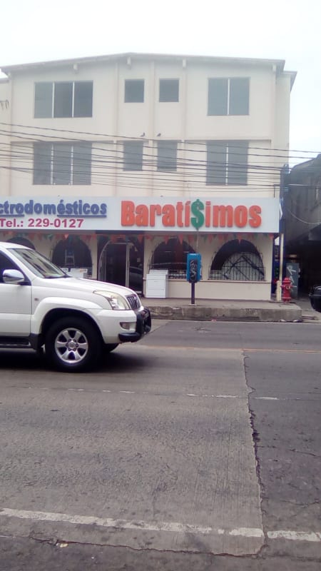White two-story building with commercial signage and parking at Edificio 15 Panama City