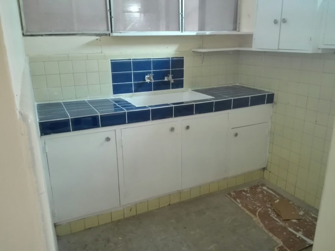 Small kitchen with blue tile countertop, cabinets, and large window in Edificio 15 near Metro Panama