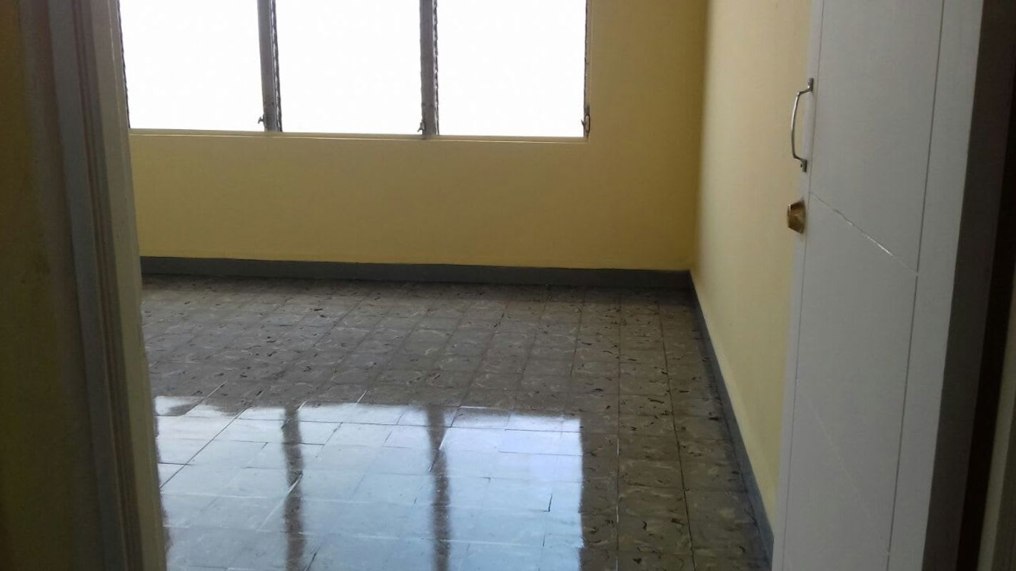 Empty bright room with yellow walls, large window, tile flooring at Edificio 15 Panama City