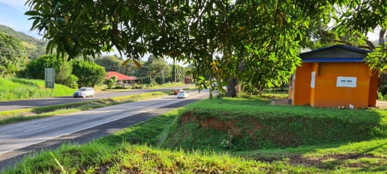Panoramic view of orange building, lush green grass, trees beside Pan-American Highway in Sajalices Chame Panama