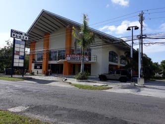 Exterior facade of PH Coronado Plaza commercial building with parking lot and palm trees in Nueva Gorgona
