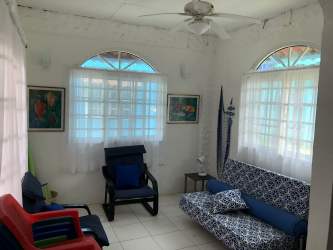 Bright bedroom with windows, curtains, wooden dressers in Isla Grande Caribbean home Panama