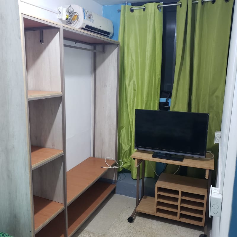 Small bedroom furnished with AC unit, open wardrobe, window in PH Via España Plaza Panama City