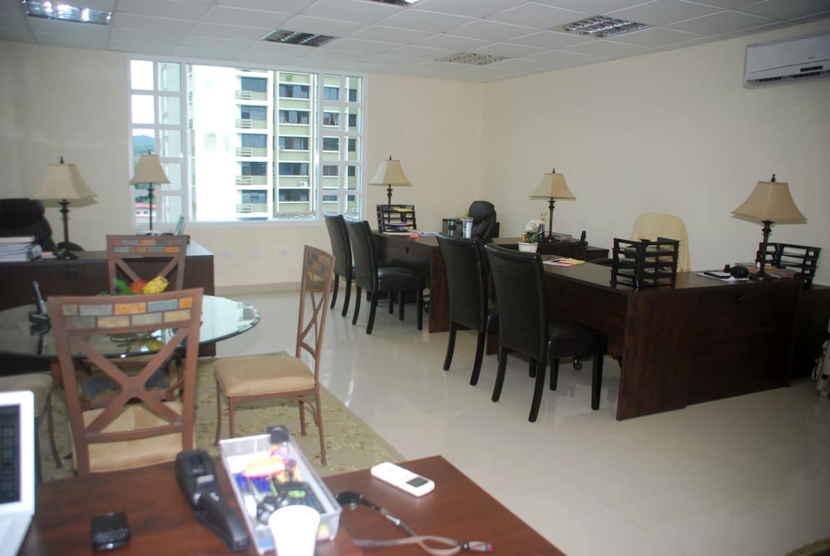 Contemporary office with round glass table, multiple desks and large windows in Camino de Cruces Business Center Panama City
