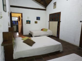 Bedroom with terracotta floors, multiple beds, natural light and garden view in Isla Grande beachfront villa