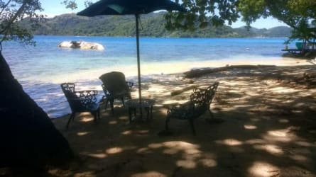 Rustic bedroom with exposed wooden ceiling beams, tiled floor and double beds on Isla Grande beach house