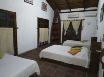 Large bedroom with exposed beams, AC, brick floors and multiple beds in Isla Grande