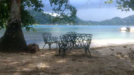 Outdoor seating on sandy beachfront with shade trees and ocean view Isla Grande Colón Panama