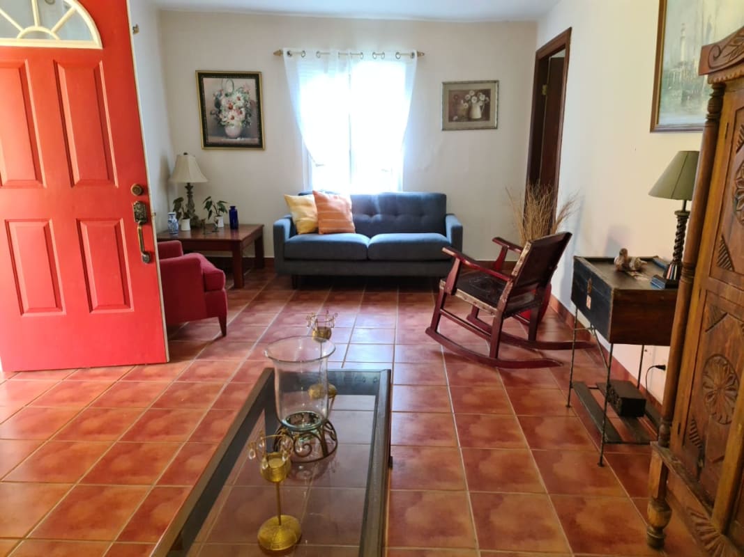 Spacious rustic living area with teal sofa, bay window, wooden beams in Coclé Panama