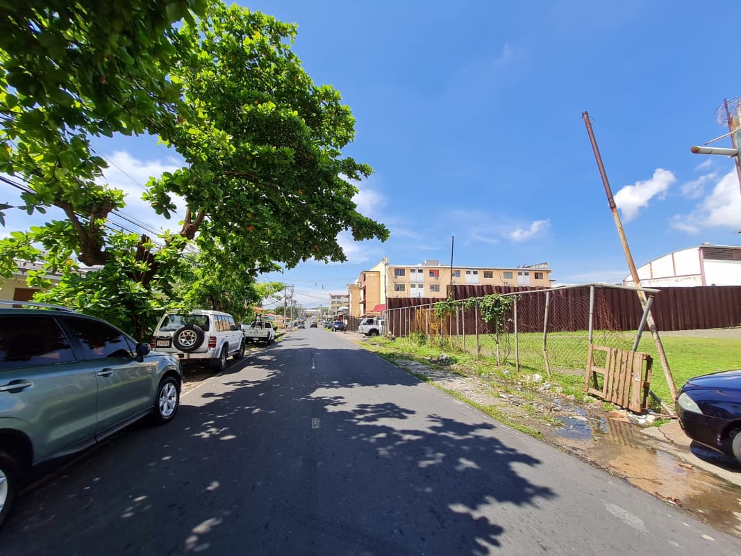 Urban street with cars and empty fenced lot in Panama City Rio Abajo