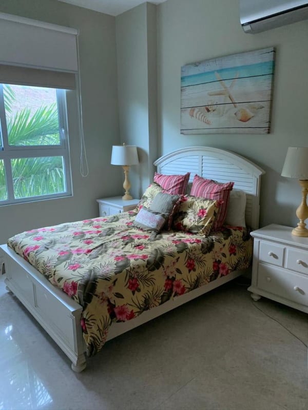 Master bedroom with ocean views, floral decor, large window, AC at Bijao Beach Condo Panama