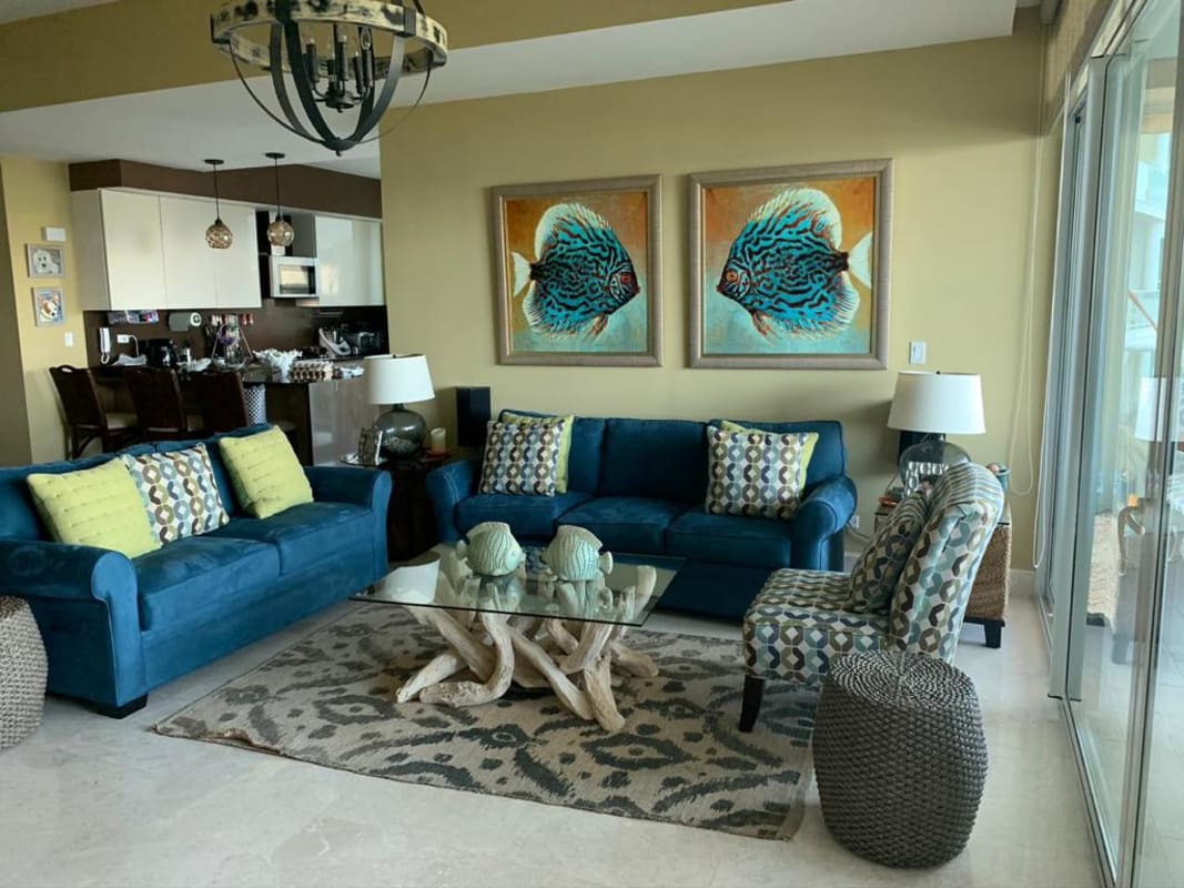 Coastal living room with blue sofas, driftwood coffee table, large glass doors at Bijao Condo Panama
