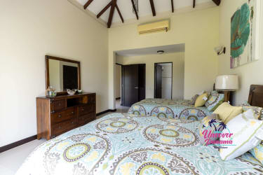 Bedroom with two queen beds, vaulted ceiling, tropical style decor in coastal golf villa Panama