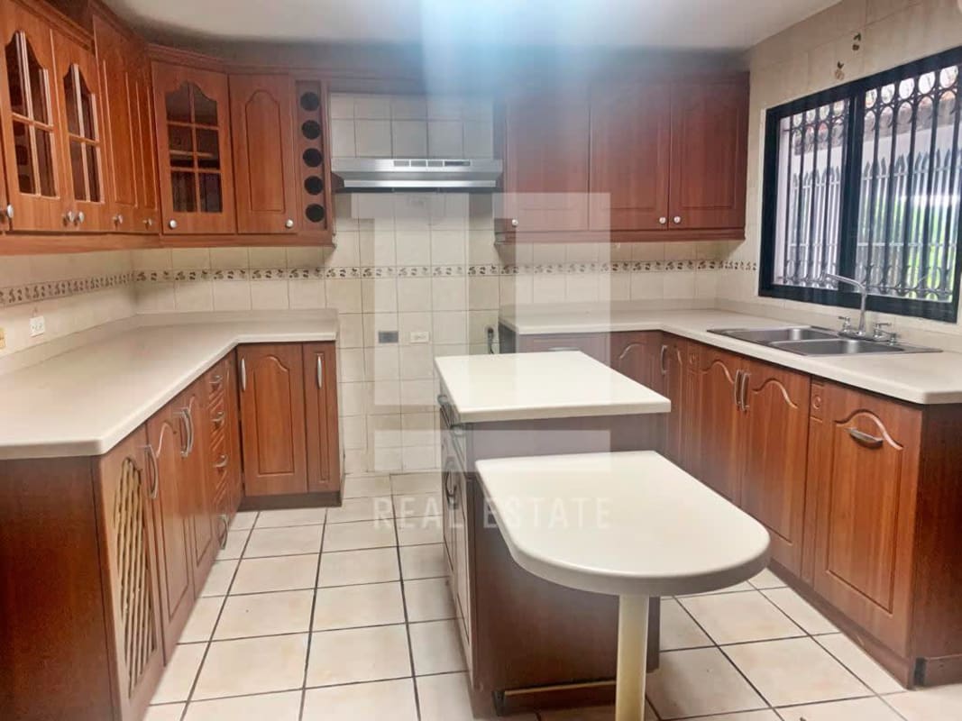 Spacious kitchen featuring wooden cabinets, island, double sink in Dos Mares Panama house