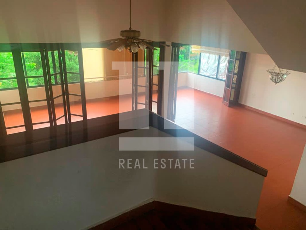 Open-plan living space with folding glass doors, terracotta floor facing green backyard in Dos Mares house Panama