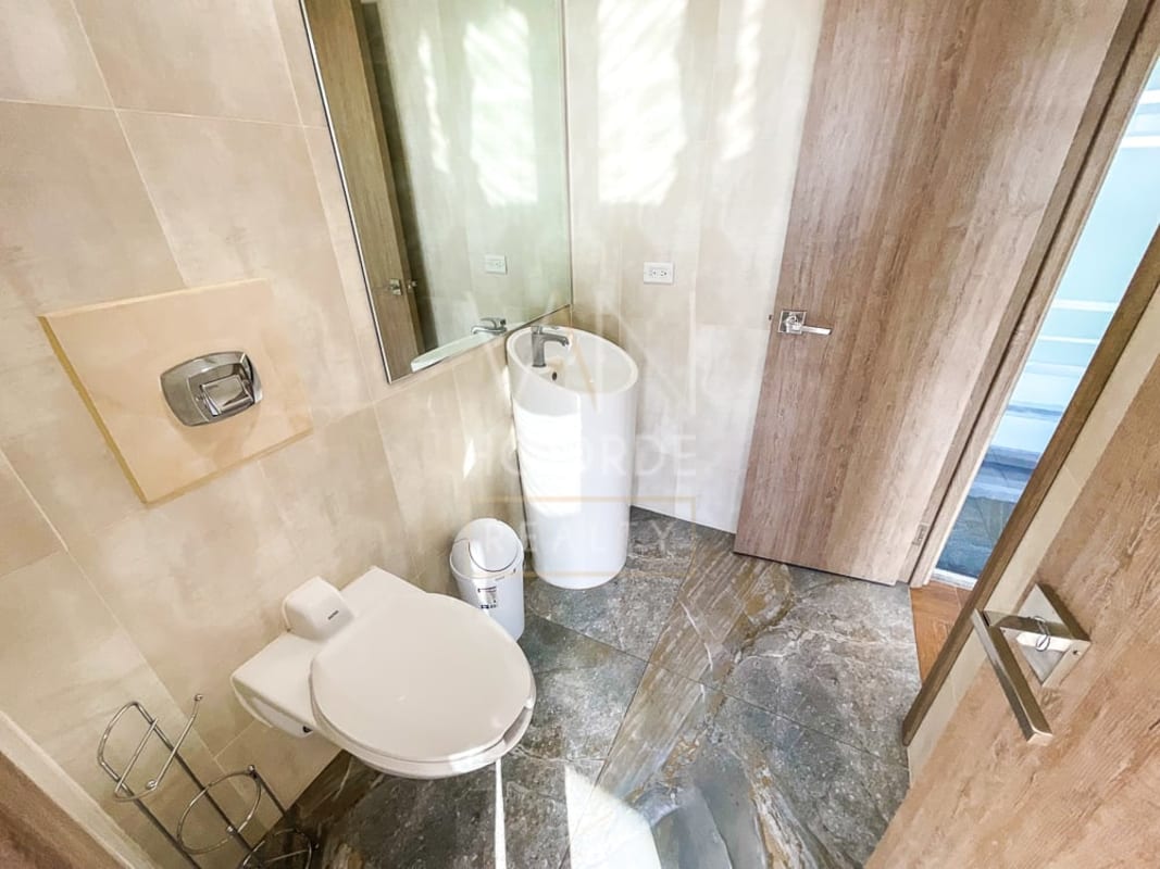 Minimalist bathroom with wall-mounted toilet, pedestal sink marble-like floors Torre Arifa Panama