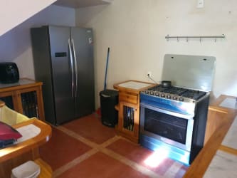 Rustic kitchen under staircase with wooden cabinets, stainless appliances in beachfront Ocean Loft Pedasi house