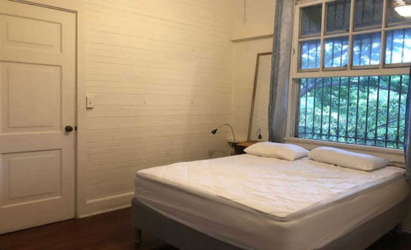 Simple minimalist bedroom with wood panel walls and natural light Herrick Heights Ancon Panama