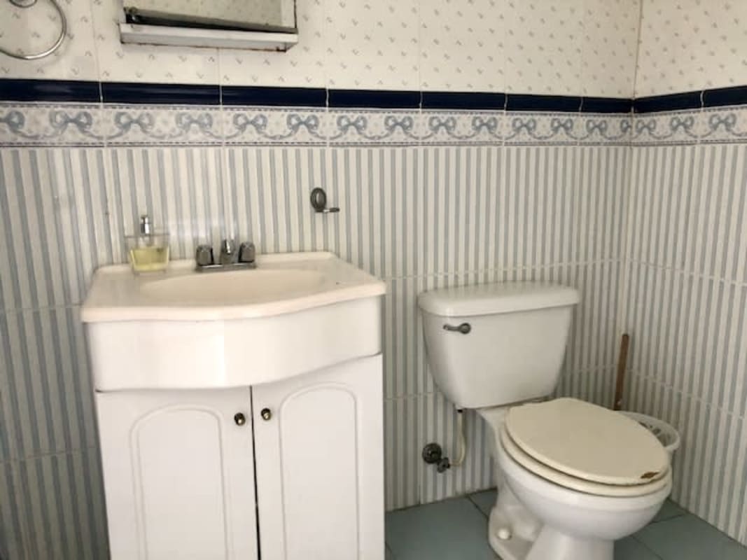 Bathroom with blue and white tiles, vanity and mirror Herrick Heights Ancon Panama home