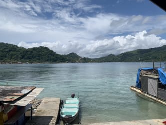 Dock with boat on quiet lake with mountain panorama in Isla Grande Panama