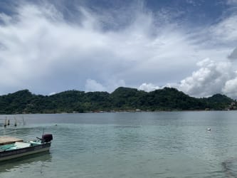 Scenic waterfront with calm waters, hills, dock and boat in Isla Grande Portobelo Panama