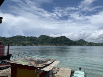 Rustic Caribbean style house with balcony, green trim, surrounded by vegetation in Isla Grande