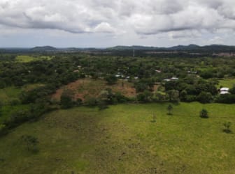 Rural landscape with open green fields, small trees, mountain backdrop, Chiriquí Panama