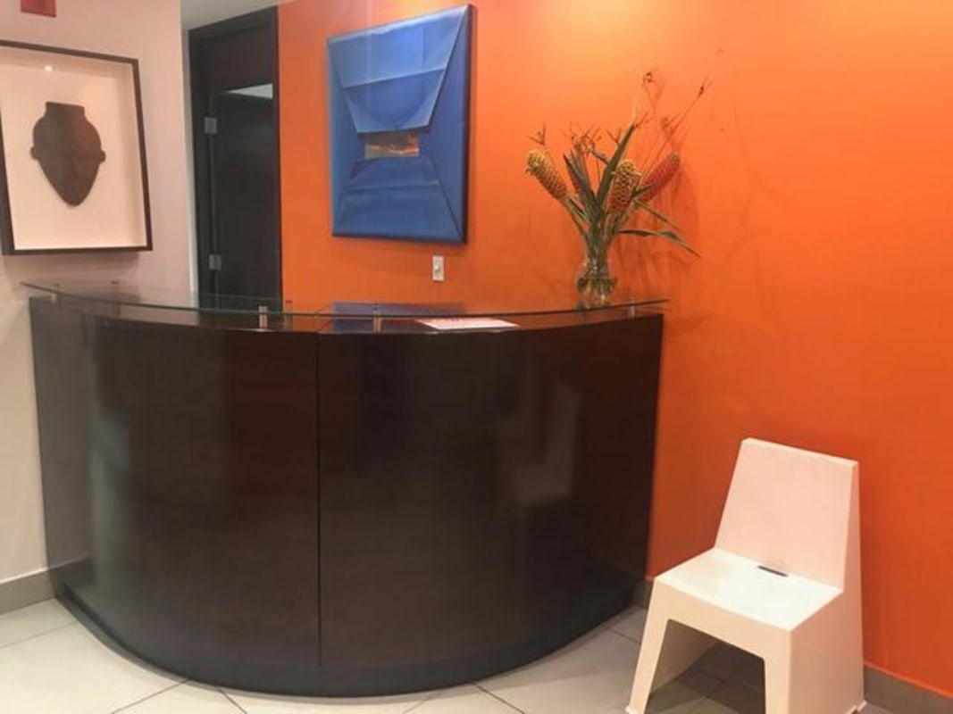Curved wood reception desk with glass top orange wall Panama office for sale