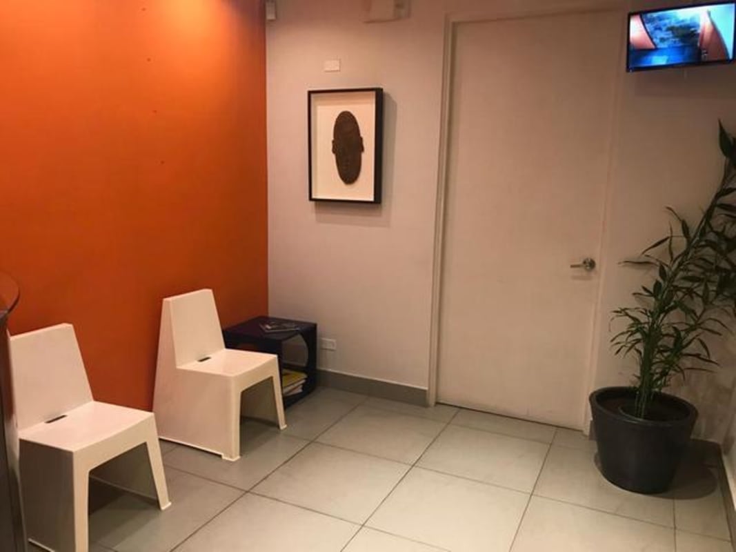 Waiting area with orange wall, chairs, plant in commercial building in Panama