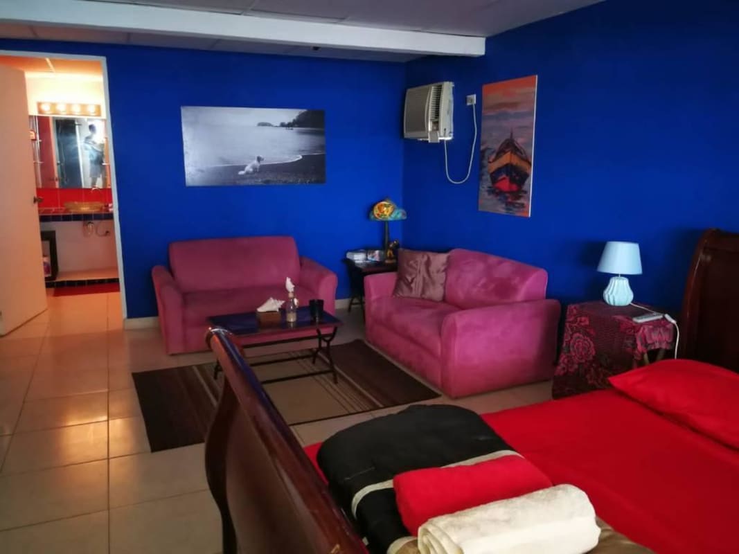 Bedroom with yellow walls, AC unit, and colorful bedding in Buenaventura Panama beach villa