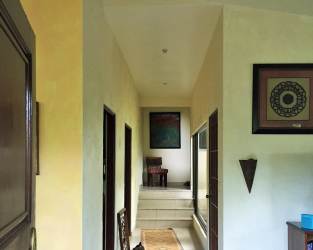 Exterior of mountain villa with lush trees and wrap-around porch in Altos del María Siena Panama