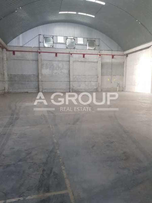 Empty industrial warehouse interior showing high ceilings, concrete walls, and ventilation fans