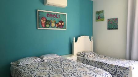 Bedroom with twin beds, blue accent wall, artwork and air conditioning in VistaMar Villa Panama